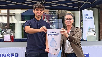 Zwei MItarbeiter der Stadtwerke Schwerte halten symbolisch einen großen Trinkbecher in die Kamera