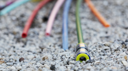 Glasfaserausbau in Ergste wird fortgesetzt Auf dem Bild sieht man mehrere bunte Glasfaserkabel auf dem Boden liegen. Es deutet alles auf eine Baustelle hin.