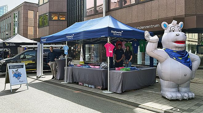 Der Stand der Stadtwerk Schwerte. Davor steht ein XXL-Nilpferd und viele bunte T-Shirts hängen an dem Verkaufszelt, das ein blaues Dach hat.