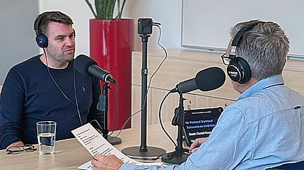 Aufnahme des Stadtwerke-Podcasts BlauPause mit Gastgeber Jörg Przystow (rechts) im Gespräch mit dem neuen Stadtbadleiter Daniel Knapp. Beide sitzen an einem Tisch mit Kopfhörern und großen Mikrofonen.
