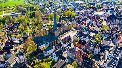 Drohnenaufnahme der Stadt Schwerte mit einem Kirchturm in der Bildmitte umgeben von vielen Häusern.