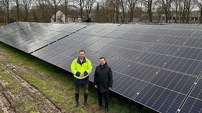 Sebastian Kirchmann und Dimitrios Axourgos  vor einer großen Freiflächenphotovoltaikanlage.