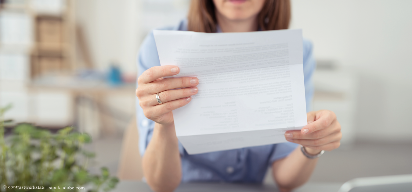 Eine Frau sitz an einem Tisch und hält ein Schreiben in den Händen als Symbolbild für die jährlichen Verbrauchsabrechnungen