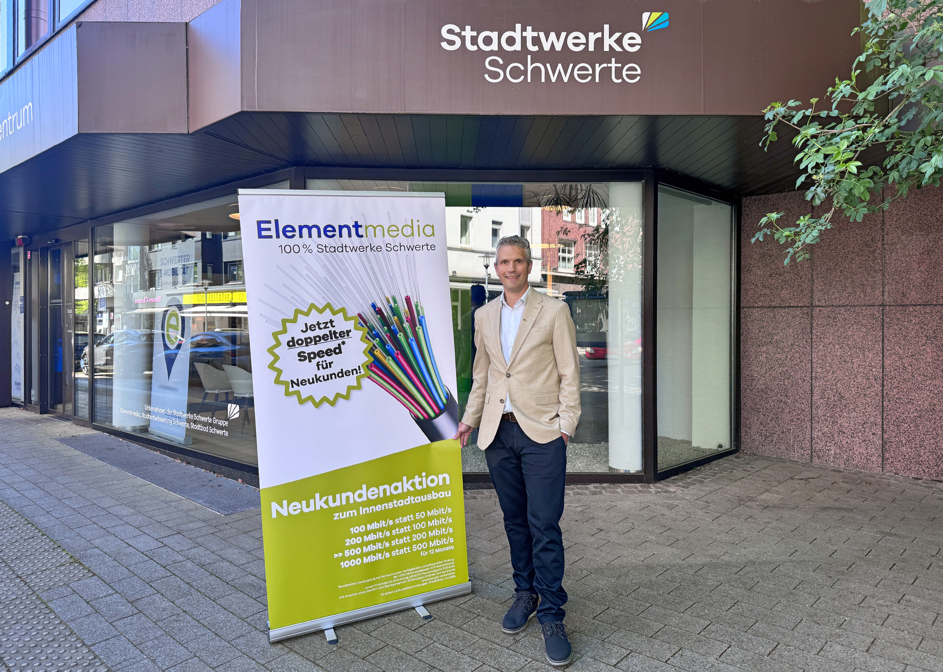 Ein Mitarbeitet der Elementmedia steht vor dem Kundenzentrum der Stadtwerke Schwerte und bewirbt eine Neukundenaktion für den verkaufsoffenen Sonntag in Schwerte