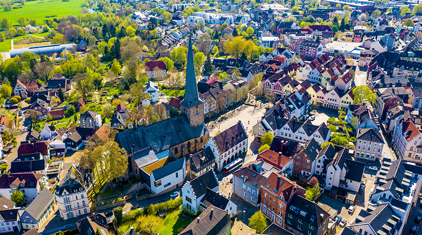 Drohnenaufnahme der Stadt Schwerte mit einem Kirchturm in der Bildmitte umgeben von vielen Häusern.