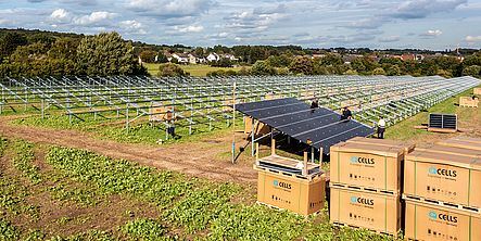 Erste Montagearbeiten am Solarpark. Kisten mit Modulen stehen vor dem Gerüst der Photovoltaikanlage.