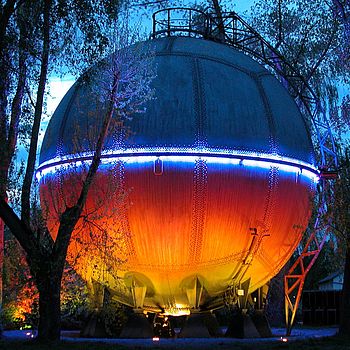 Der historische Gaskugelbehälter auf dem Gelände der Stadtwerke Schwerte blau und orange beleuchtet.