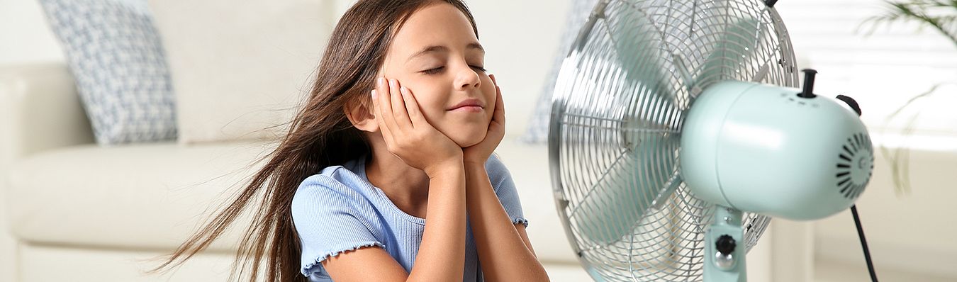 Ein Mädchen sitzt vor einem Ventilator und lässt sich den Wind ins Gesicht pusten. Als Symbolbild für unseren Strom für Schwerte.