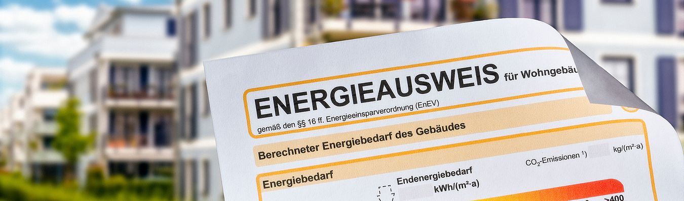 Oberer Teil von einem Energieausweis einer Immobilie. Im Hintergrund ist die Baustelle einer Immobilie zu sehen.