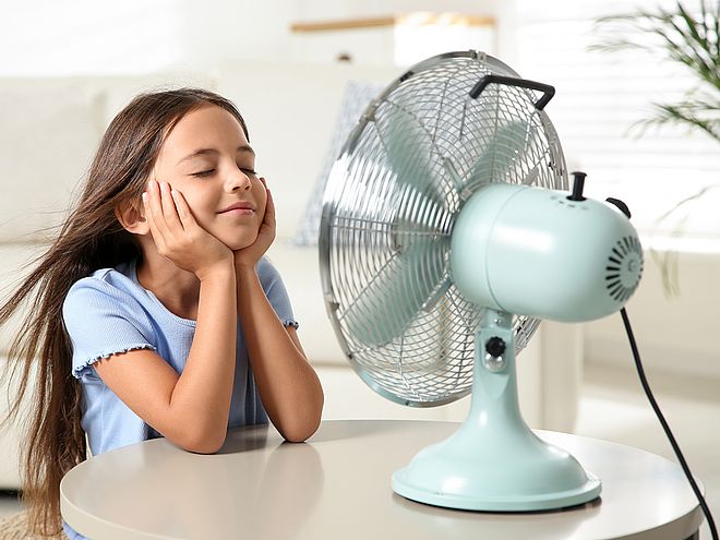Ein Mädchen sitzt vor einem Ventilator und lässt sich den Wind ins Gesicht pusten. Als Symbolbild für unseren Strom für Schwerte.